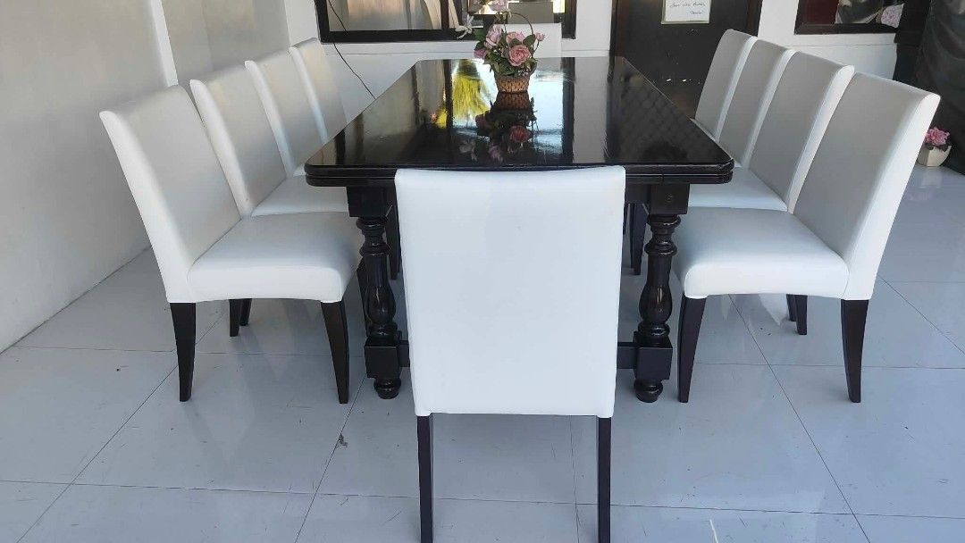 Large dark wood dining table with eight white chairs (Category: Tables & Sets) located in Manila. Submitted by roveeeeelen_06 (Listing ID 1469418864, Image 2). Description: - Elegant rectangular dining table with a dark polished wood finish - Includes 8 matching high-back chairs upholstered in smooth white synthetic leather - Sturdy frame that comfortably seats 8 people, ideal for family gatherings - Overall clean upholstery - Minor scuffs on tab
