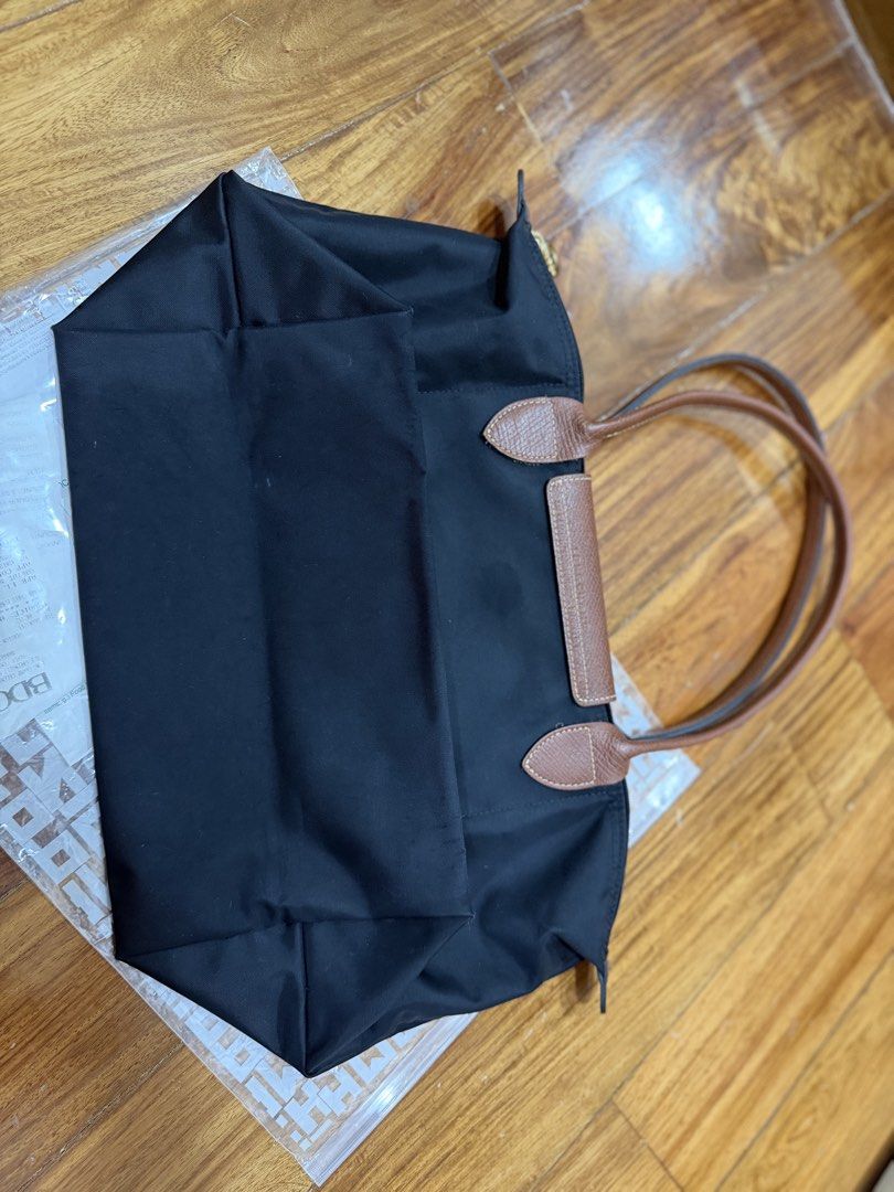 Longchamp Le Pliage Nylon Tote Bag Black (Category: Luxury Bags & Wallets) located in Quezon City. Submitted by chrispineda (Listing ID 1469491406, Image 2). Description: - Brand/Model: Longchamp Le Pliage Tote Bag - Color: Classic black nylon with brown leather handles and flap - Hardware: Gold-tone with snap button closure - Features: Lightweight, foldable design with a spacious interior - Best For: Daily commute, work, school, or travel - Cond