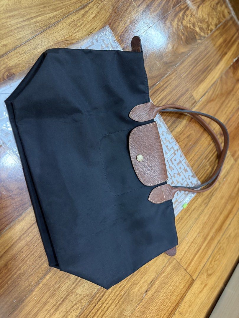 Longchamp Le Pliage Nylon Tote Bag Black (Category: Luxury Bags & Wallets) located in Quezon City. Submitted by chrispineda (Listing ID 1469491406, Image 3). Description: - Brand/Model: Longchamp Le Pliage Tote Bag - Color: Classic black nylon with brown leather handles and flap - Hardware: Gold-tone with snap button closure - Features: Lightweight, foldable design with a spacious interior - Best For: Daily commute, work, school, or travel - Cond