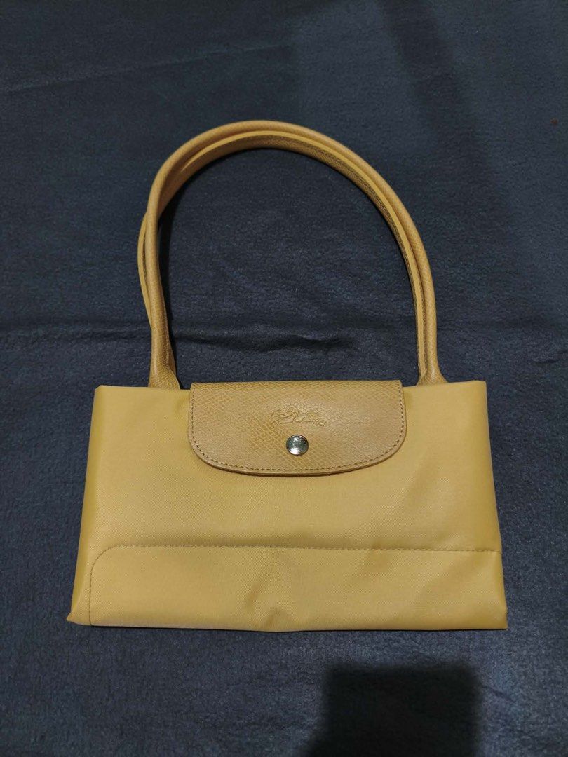 Longchamp Yellow Tote Bag (Category: Tote Bags) located in Quezon City. Submitted by leilumiereclassique (Listing ID 1469412857, Image 1). Description: - Authentic Yellow Longchamp tote bag - Durable nylon material with genuine leather handles and flap closure - Features snap button with iconic embossed horse logo - Spacious interior perfect for daily essentials - Convenient foldable design for easy storage - Clean condition, includes protective 