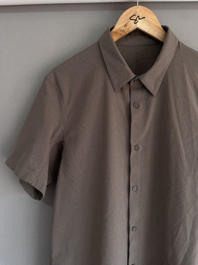 Lululemon Short Sleeve Button Up Shirt Brown Grid (Category: Tshirts & Polo Shirts ) located in Mataasnakahoy. Submitted by zero4thrift (Listing ID 1469429463, Image 2). Description: - Brand: Lululemon - Style: Brown grid-pattern short sleeve button-front shirt with classic collar - Fabric: Textured, lightweight material designed to keep you cool - Details: Subtle logo tag on the lower side seam, extra replacement button included - Condition: Exc