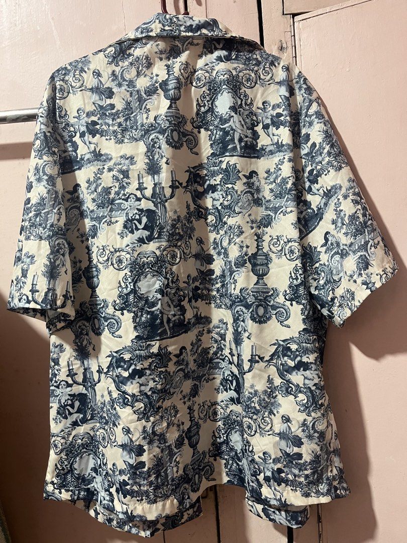 Manfinity Blue White Baroque Print Button Down Shirt Size S (Category: Formal Shirts) located in Manila. Submitted by pinkmowchiiii (Listing ID 1469537375, Image 2). Description: Manfinity short sleeve button down shirt. Size S, fits true to size. Cream base with blue and black baroque style toile print depicting cherubs, urns, and scrolling patterns. Camp collar neckline, regular fit, lightweight fabric. Great statement piece for summer or casua