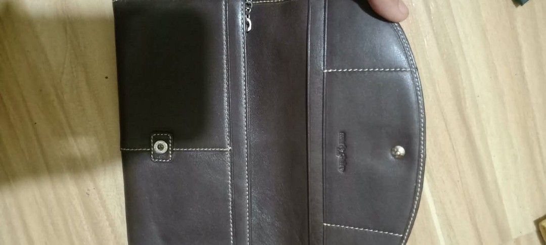 Marie Claire brown leather long wallet (Category: Wallets & Card holders) located in Gapan. Submitted by montesnora80204 (Listing ID 1469436059, Image 2). Description: - Brand: Marie Claire - Color: Dark brown leather with pink patterned interior lining - Closure: Flap closure with front metal logo tag and debossed logo on the back - Interior Features: Multiple card slots, slip compartments, and a zippered coin pocket - Special Detail: Adorable f