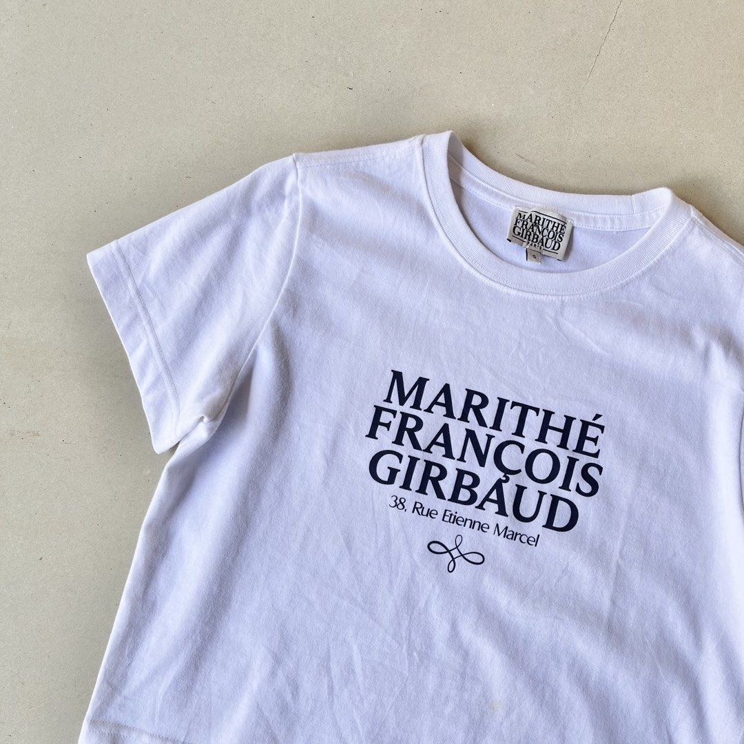 Marithe Francois Girbaud White Logo T-shirt (Category: Shirts) located in Mandaue City. Submitted by chinsyap_03 (Listing ID 1469465847, Image 3). Description: - Brand: Marithé François Girbaud - Color: Clean bright white - Design: Classic block lettering with Paris address detail - Fit: Cropped, boxy fit with short sleeves and crew neck - Size: Tagged S (fits S-M nicely) - Styling: Perfect with baggy denim or cargo pants.