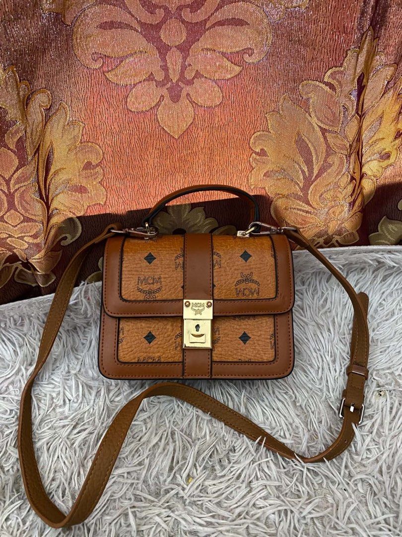 MCM Brown Monogram Crossbody Bag with Top Handle (Category: Luxury Bags & Wallets) located in Manila. Submitted by melissatua68314 (Listing ID 1469518097, Image 1). Description: - Brown MCM monogram crossbody bag - Structured silhouette with a chic top handle and adjustable shoulder strap - Secure gold-tone front lock closure - Clean fabric-lined interior featuring a convenient zipped middle compartment and slip pockets.