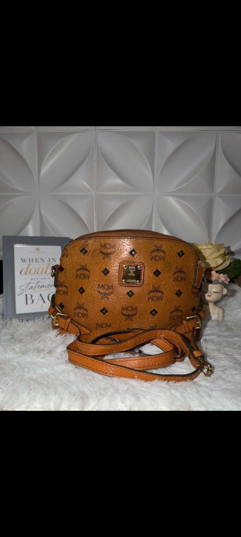 MCM Cognac Visetos Dome Crossbody Bag (Category: Luxury Bags & Wallets) located in Manila. Submitted by 29chi (Listing ID 1469534538, Image 1). Description: - Brand: MCM - Style: Dome Crossbody Bag - Color: Cognac Brown - Material: Signature Monogram Coated Canvas - Hardware: Gold Tone - Details: Front metal logo plaque with serial number, top zipper closure, attached adjustable leather strap - Condition/Use: Compact size, perfect for everyday we