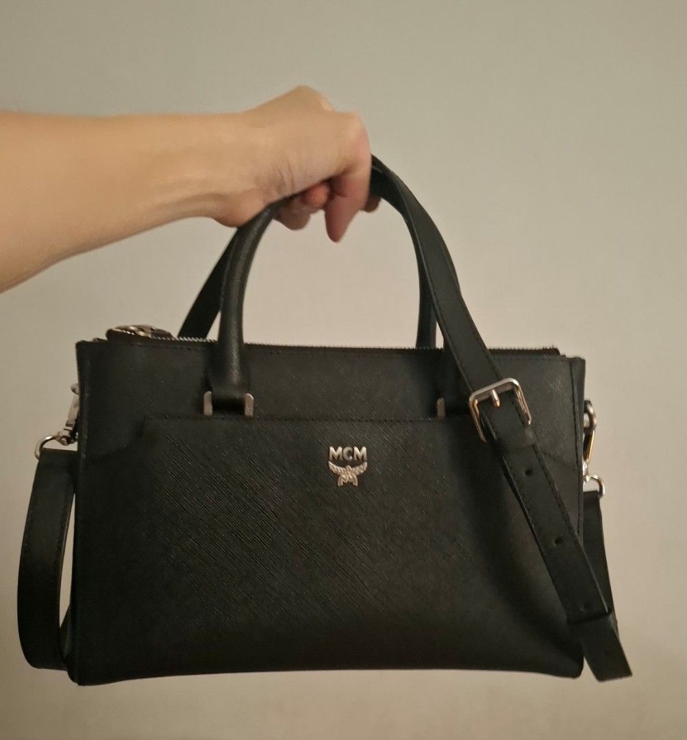 MCM elda bag (ORIGINAL. LIMITED EDITION. Hard to source bag!) (Category: Luxury Bags & Wallets) located in Pasay City. Submitted by kgemsluxuryboutique (Listing ID 1469453352, Image 2). Description: - Brand: MCM - Material: Structured saffiano leather - Color: Classic Black with silver-tone hardware - Features: Front pocket with metal logo plate, double top handles, and an adjustable/detachable shoulder strap - Interior: Monogram fabric lining wi