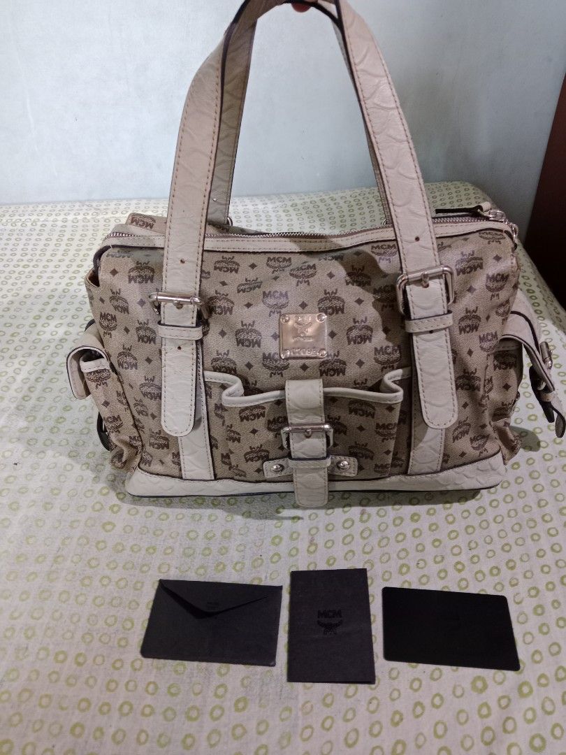 MCM Monogram Tote Handbag with Dual Straps and Pockets (Category: Luxury Bags & Wallets) located in Bacolod City. Submitted by jorengrate26639 (Listing ID 1469436493, Image 1). Description: - Vintage Authentic MCM Tote Bag beige monogram canvas - Elegant white leather trim with dual buckle-detail shoulder handles - Functional exterior front pocket and side utility pockets with buckle closures - Secure zip-top closure with branded hardware pulls -