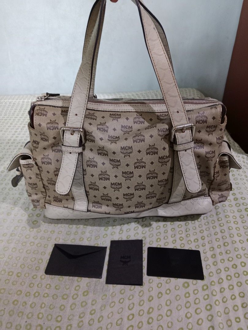 MCM Monogram Tote Handbag with Dual Straps and Pockets (Category: Luxury Bags & Wallets) located in Bacolod City. Submitted by jorengrate26639 (Listing ID 1469436493, Image 2). Description: - Vintage Authentic MCM Tote Bag beige monogram canvas - Elegant white leather trim with dual buckle-detail shoulder handles - Functional exterior front pocket and side utility pockets with buckle closures - Secure zip-top closure with branded hardware pulls -