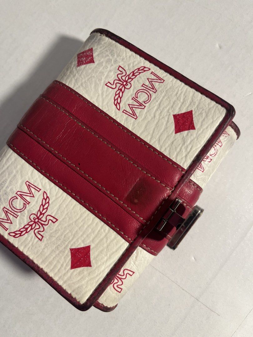 MCM White and Red Tri-Fold Wallet (Category: Luxury Bags & Wallets) located in Muntinlupa City. Submitted by pique.unique (Listing ID 1469536157, Image 3). Description: - Brand: MCM - Authenticity Guaranteed - Design: White and red signature print tri-fold wallet with metal closure plate - Interior: Vibrant hot pink leather lining with debossed MCM München logo - Features: Multiple card slots and a convenient ID window - Size: Compact, ideal for 