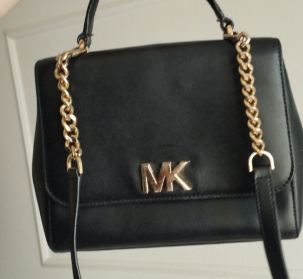 Michael Kors Black Leather Handbag with Gold Chain Strap (Category: Cross-body Bags) located in Manila. Submitted by lene48 (Listing ID 1469509389, Image 1). Description: - Brand: Michael Kors - Material: Premium black leather with gold-tone hardware - Straps: Features both a top handle and a removable strap for versatile styling - Closure: Front flap with statement MK logo hardware - Interior: Black fabric lining with a convenient zip pocket and