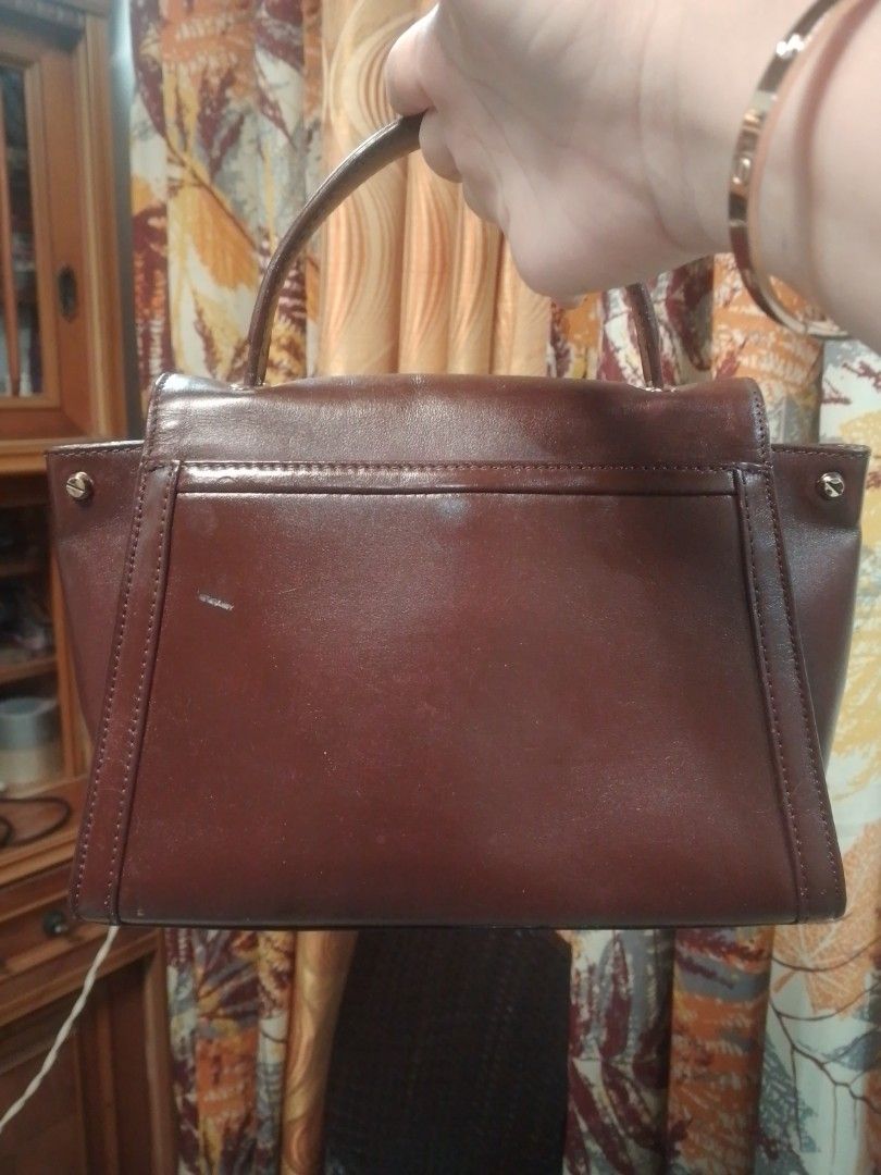 Michael Kors Brown Leather Top Handle Handbag (Category: Luxury Bags & Wallets) located in Manila. Submitted by annemil_1984 (Listing ID 1469451372, Image 3). Description: - Brand: Michael Kors - Color/Material: Rich brown leather - Style: Structured trapezoid top handle bag with a flap closure - Hardware: Gold-tone geometric metal clasp with visible scuffs - Condition: Minor surface marks on the leather body, hardware shows wear - Features: Sing