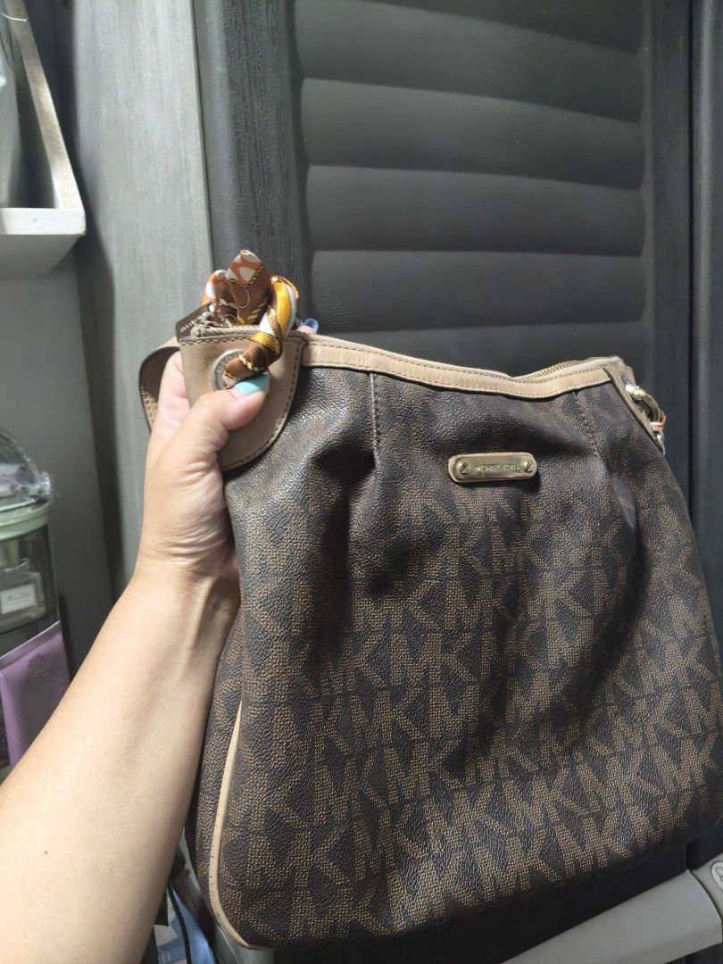 Michael Kors Brown Monogram Hobo Shoulder Bag (Category: Shoulder Bags) located in Manila. Submitted by stuff_finder (Listing ID 1469424113, Image 1). Description: - Brand: Michael Kors - Material: Brown monogram canvas with beige leather trim - Hardware: Gold-tone with engraved front logo plaque - Accents: Includes a stylish printed twilly scarf tied to the strap rings - Interior: Multiple compartments, zip pockets, and clean MK logo-patterned l