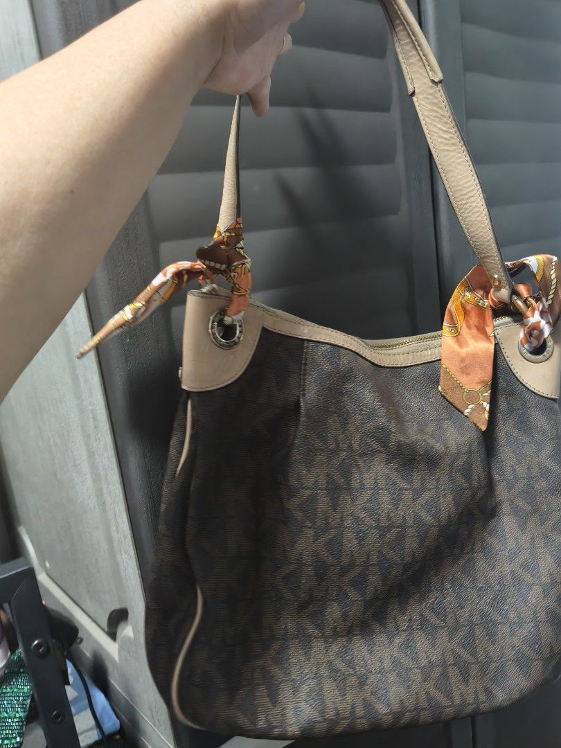 Michael Kors Brown Monogram Hobo Shoulder Bag (Category: Shoulder Bags) located in Manila. Submitted by stuff_finder (Listing ID 1469424113, Image 3). Description: - Brand: Michael Kors - Material: Brown monogram canvas with beige leather trim - Hardware: Gold-tone with engraved front logo plaque - Accents: Includes a stylish printed twilly scarf tied to the strap rings - Interior: Multiple compartments, zip pockets, and clean MK logo-patterned l
