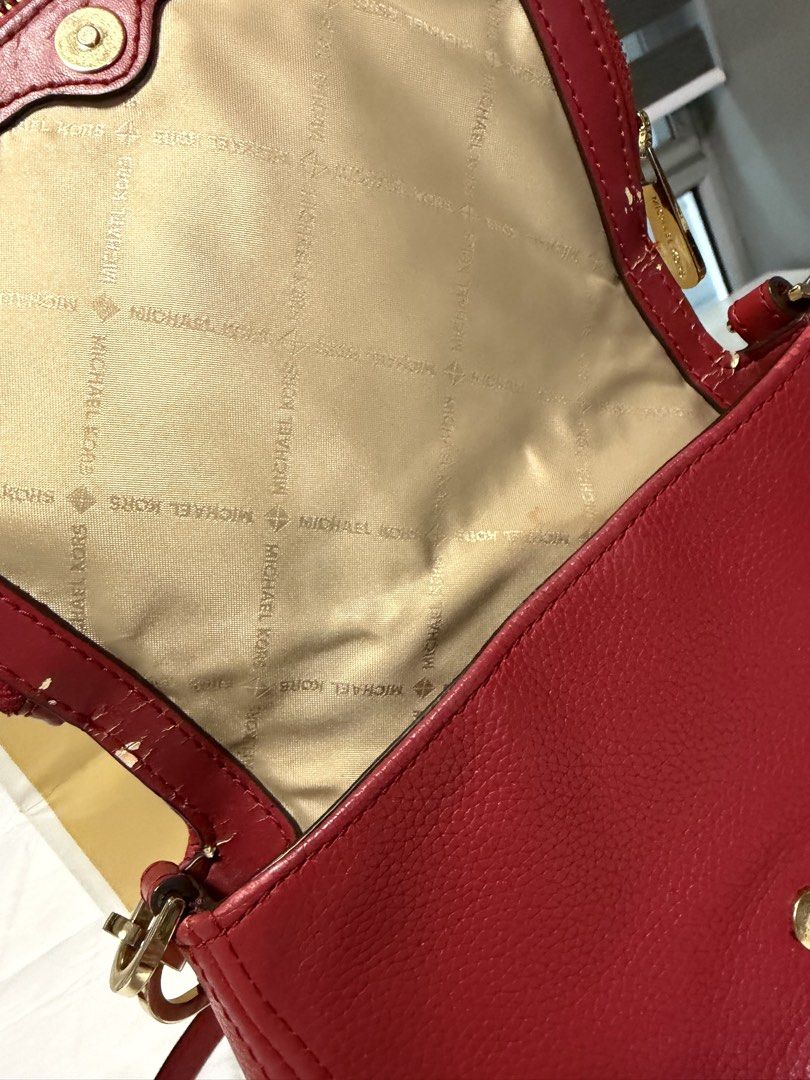 Michael Kors Red Leather Crossbody Bag (Category: Cross-body Bags) located in Manila. Submitted by chanelmari19 (Listing ID 1469402250, Image 2). Description: - Brand: Michael Kors - Material: Bright red pebble leather with gold hardware - Features: Adjustable buckle strap, MK logo interior lining, secure zip closure - Included: Matching beige Michael Kors shopping bag - Condition: Good overall, minor flaking visible along some interior edge seam