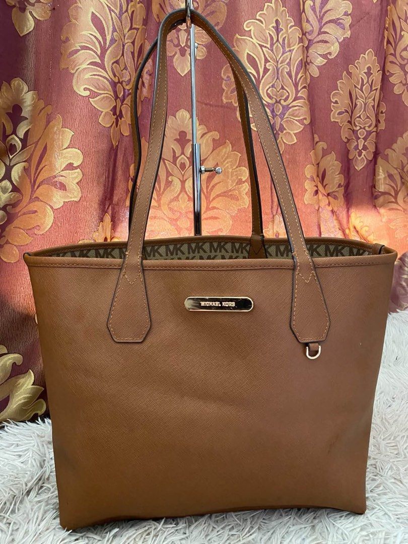Michael Kors reversible brown MK monogram tote bag (Category: Tote Bags) located in Manila. Submitted by melissatua68314 (Listing ID 1469517335, Image 2). Description: - Michael Kors reversible tote bag - Design 1: Classic all-over MK signature monogram pattern - Design 2: Solid brown Saffiano leather look - Dual top handles for comfortable shoulder wear - Elegant gold-tone MK metal logo plaque - Spacious interior, perfect for everyday essentials
