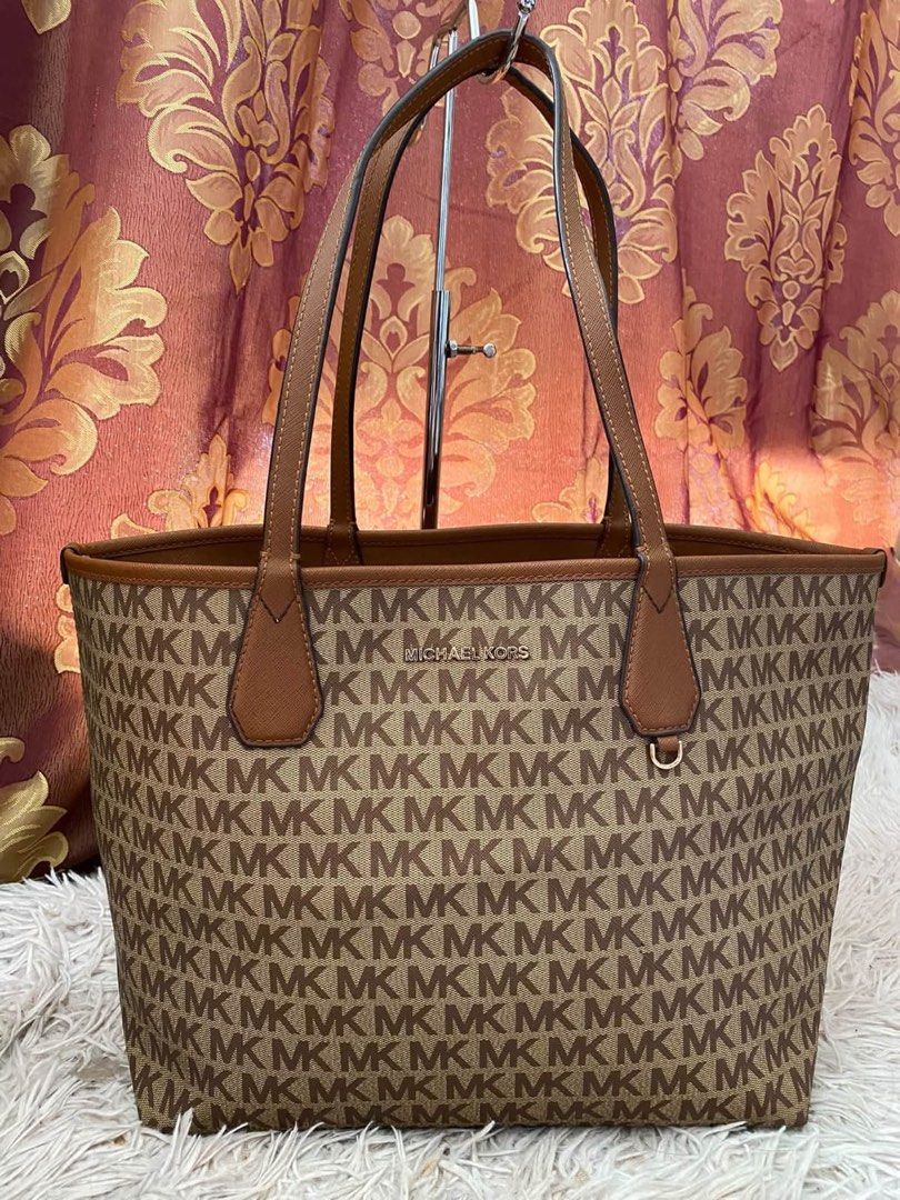 Michael Kors reversible brown MK monogram tote bag (Category: Tote Bags) located in Manila. Submitted by melissatua68314 (Listing ID 1469517335, Image 1). Description: - Michael Kors reversible tote bag - Design 1: Classic all-over MK signature monogram pattern - Design 2: Solid brown Saffiano leather look - Dual top handles for comfortable shoulder wear - Elegant gold-tone MK metal logo plaque - Spacious interior, perfect for everyday essentials