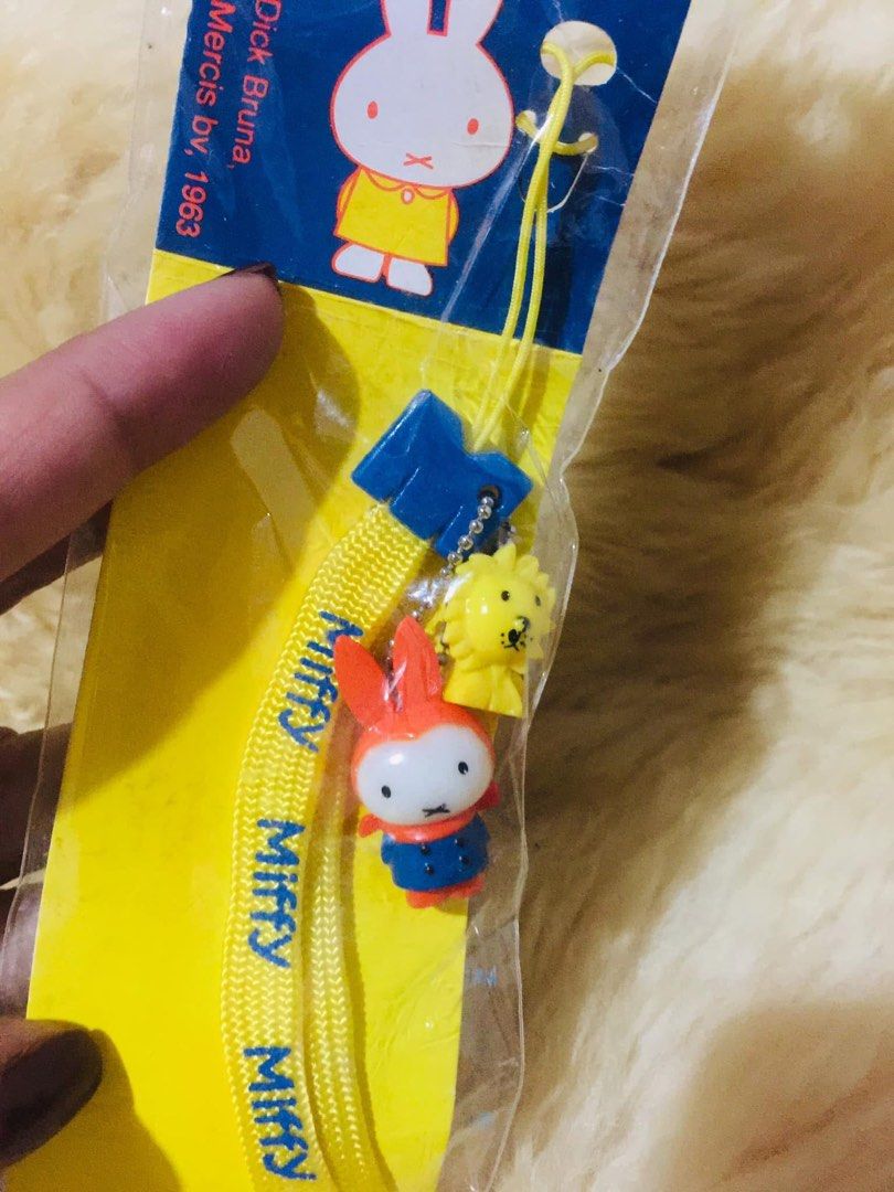 Miffy Strap Yellow Blue Orange Character Charm Phone Strap (Category: Character Goods) located in Baguio. Submitted by izza_thrifty (Listing ID 1469403514, Image 2). Description: - 100% authentic Miffy merchandise in original unopened packaging - Vibrant yellow woven lanyard with stylish blue Miffy text - Includes 3 cute charms: blue 'M' symbol, yellow lion, and orange-suited Miffy figurine - Official Dick Bruna Mercis bv (1963 copyright) collect