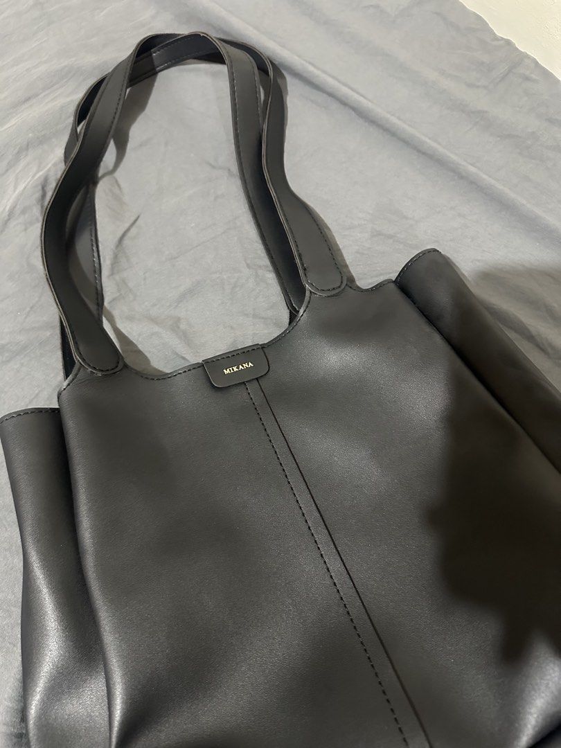 Mikana Black Shoulder Bag Tote (Category: Shoulder Bags) located in Taytay. Submitted by declutter_random (Listing ID 1469543364, Image 1). Description: - Brand: Mikana - Material: Smooth black faux leather - Design: Minimalist with center vertical stitching and small logo patch - Straps: Dual shoulder straps - Features: Structured base and clean interior - Capacity: Roomy enough for daily essentials, work, or school RFS: nakatambak lang hindi na