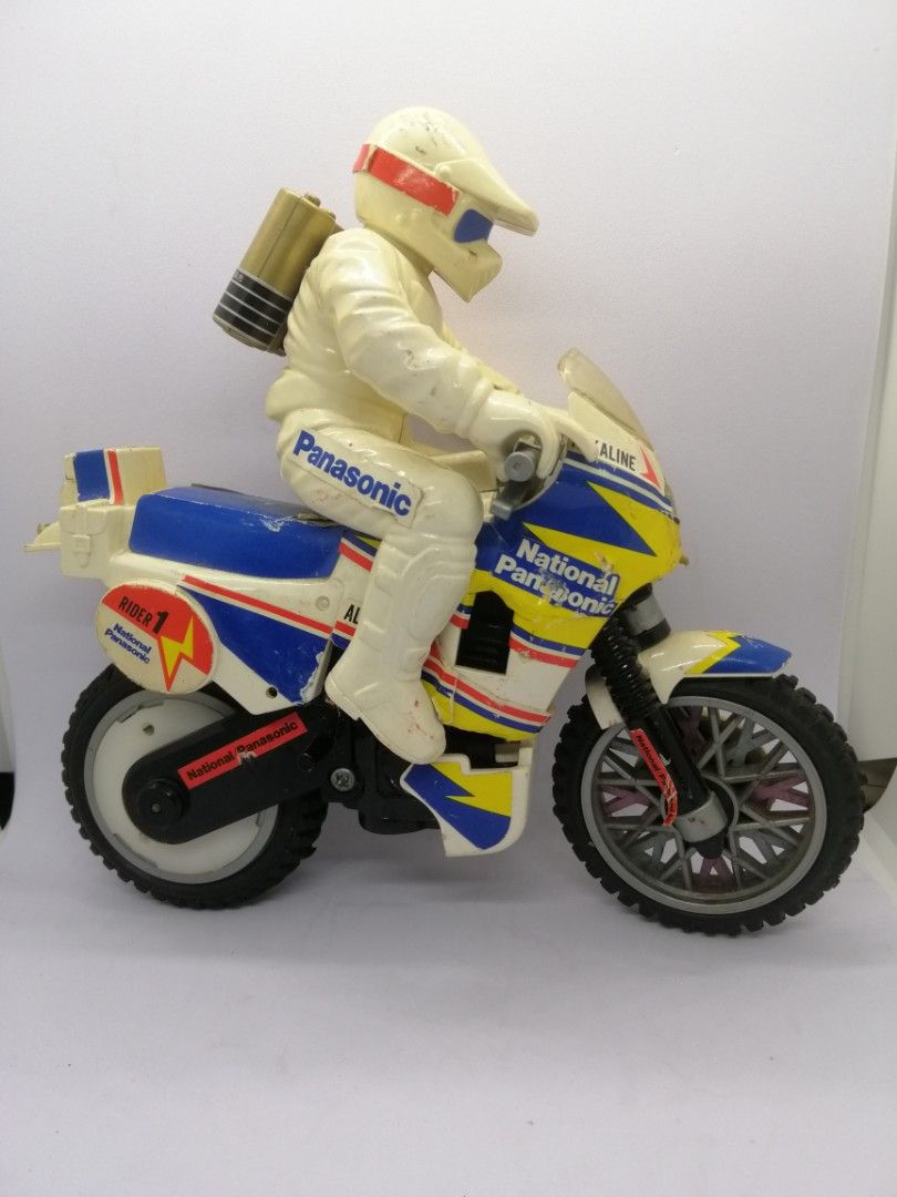 Motorcycle national panasonic promo display (Category: Vintage Collectibles) located in Quezon City. Submitted by goldencity1964 (Listing ID 1469537297, Image 1). Description: This is a vintage battery-operated toy motorcycle and rider produced under the National Panasonic (Matsushita) brand. ​Design & Details: The toy features a dirt-bike style layout with a rider in a matching cream-colored jumpsuit and helmet, complete with a faux battery tank
