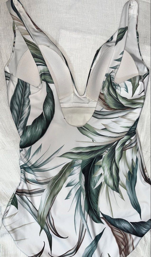 NEXT Botanical Leaf Print One Piece Swimsuit (Category: Bikinis & Swimsuits) located in General Mariano Alvarez. Submitted by kascade (Listing ID 1469536241, Image 1). Description: - Brand: Next - Style: One-piece swimsuit with V-neckline and twisted front detail - Color/Pattern: Green botanical leaf print on a crisp white background - Support: Built-in padded cups for shape and comfort - Coverage: Standard brief cut on the bottom - Size: L 💵 Pa
