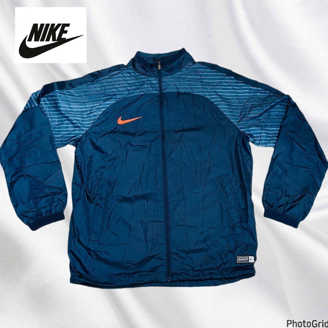 Nike | Track Jacket Windbreaker| Size M (Category: Coats, Jackets and Outerwear) located in Manila. Submitted by bengirlclothing (Listing ID 1469429496, Image 2). Description: - Brand: Nike - Size: Medium (Tag indicates Size M) - Style: Track jacket with full zip and stand collar - Color: Blue with striped sleeves and orange swoosh logo - Material: 100% recycled polyester with breathable mesh lining - Condition: Excellent / Lightweight outerwear 