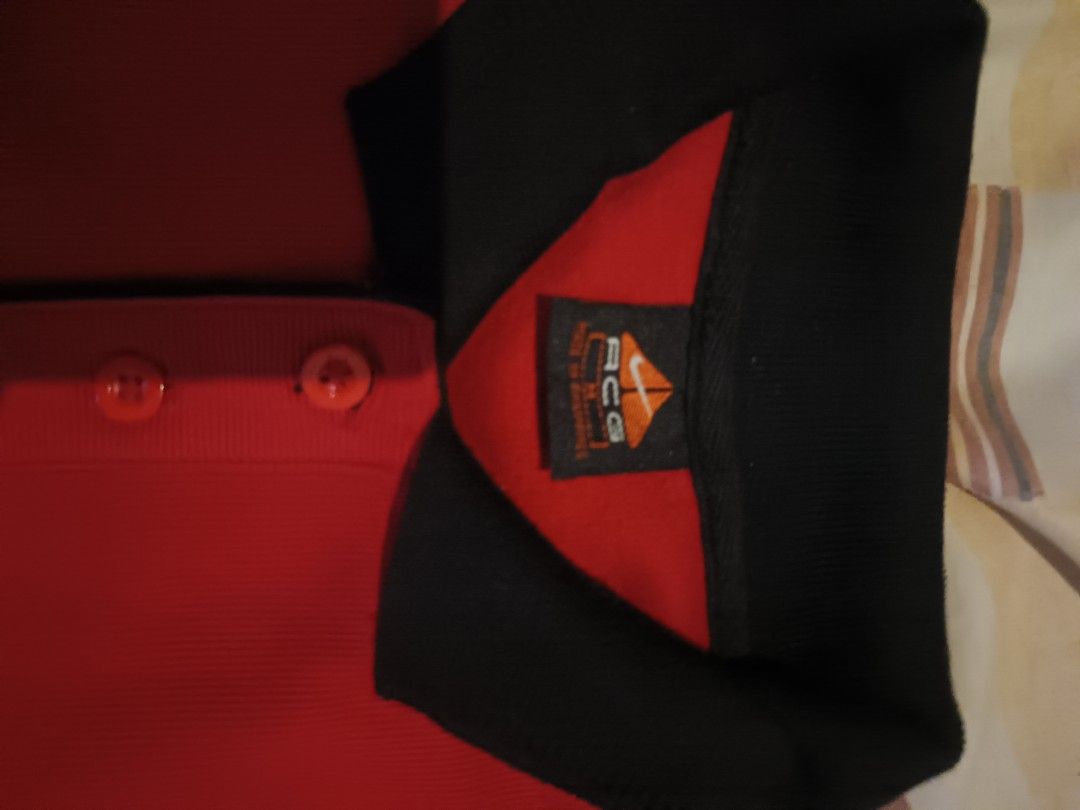 Nike. ACG polo sweetshirt (Category: Activewear) located in Odiongan. Submitted by thriftngo26 (Listing ID 1469398581, Image 2). Description: The item appears to be a vintage red Nike long-sleeve polo sweatshirt or rugby-style jumper featuring a black contrast collar, snap or button placket, ribbed cuffs and hem, and a black embroidered Nike swoosh logo on the chest.