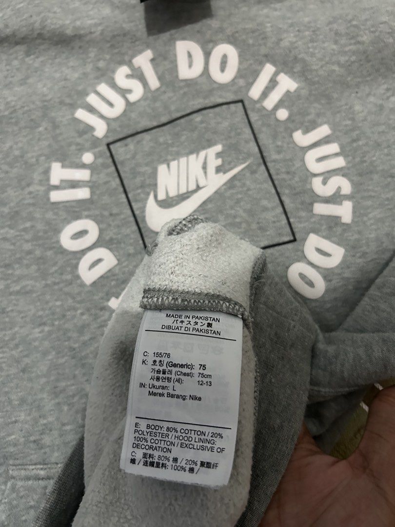 Nike Just Do It Grey Hoodie Size L (Category: Hoodies) located in Manila. Submitted by garmentfinds.01 (Listing ID 1469520963, Image 3). Description: - Authentic grey Nike pullover hoodie - Bold 'Just Do It' circular graphic on the front - Classic kangaroo pocket and standard fit - Size L (Tag indicates fit for ages 12 to 13) - Material: 80% cotton, 20% polyester body; 100% cotton hood lining - Warm, soft, and comfortable for daily use - Made in 