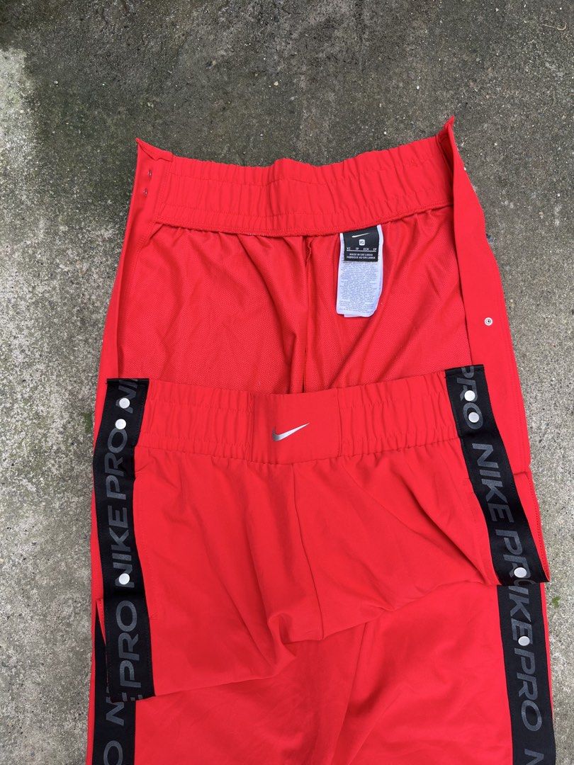 Nike Pro Red Side Snap Track Pants (Category: Joggers) located in Manila. Submitted by thrifttika (Listing ID 1469448960, Image 3). Description: Bright red Nike Pro warm-up pants. Black side taping reads Nike Pro repeatedly. Metal snap buttons run down both outer legs. Elastic waistband with a small silver Swoosh logo front and center. Size extra small tag attached inside. Made in Sri Lanka from polyester and elastane blend material. Lightweight 