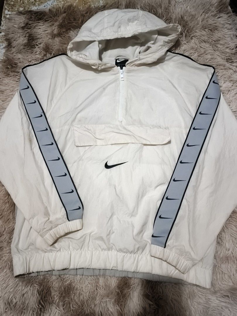 Nike Swoosh Repeat Half Zip Windbreaker White (Category: Coats, Jackets and Outerwear) located in Quezon City. Submitted by hghthrft (Listing ID 1469488314, Image 1). Description: - Brand: Nike - Item: White Windbreaker / Pullover Jacket - Size: Large - Features: Half-zip closure, attached hood, adjustable drawstrings, and front flap pocket - Design: Grey and black taped sleeves with multiple Swoosh logos and a large Swoosh printed on the back - 