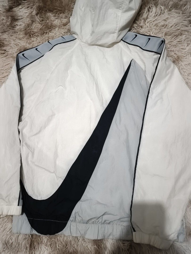 Nike Swoosh Repeat Half Zip Windbreaker White (Category: Coats, Jackets and Outerwear) located in Quezon City. Submitted by hghthrft (Listing ID 1469488314, Image 2). Description: - Brand: Nike - Item: White Windbreaker / Pullover Jacket - Size: Large - Features: Half-zip closure, attached hood, adjustable drawstrings, and front flap pocket - Design: Grey and black taped sleeves with multiple Swoosh logos and a large Swoosh printed on the back - 