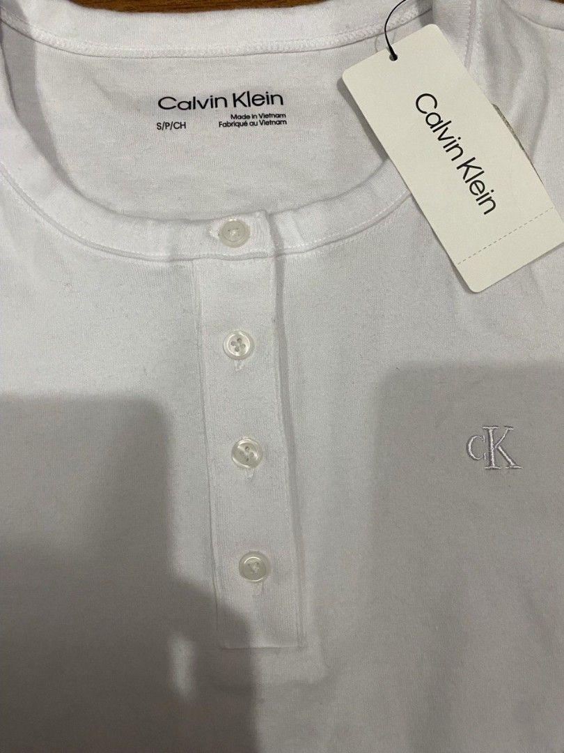 (NWT) Calvin Klein Long-Sleeve Henley Top (Category: Longsleeves) located in Gapan. Submitted by lovelypreloved1497 (Listing ID 1469428190, Image 3). Description: ✨ Brand New with Tags (NWT) Calvin Klein Long-Sleeve Henley Top ✨ Letting go of this crisp, classic women's long-sleeve knit Henley top from Calvin Klein. Features a timeless white colorway, a 4-button neckline placket, and the signature "CK" monogram emblem embroidered beautifully on t