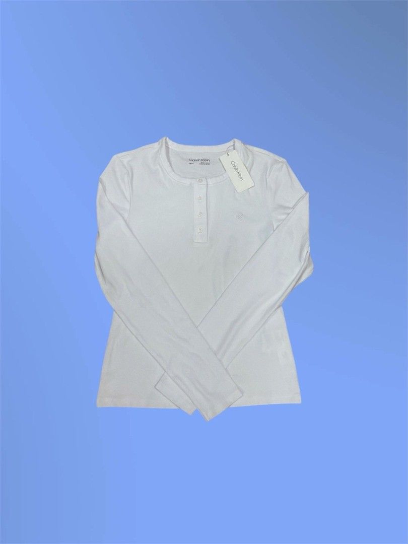 (NWT) Calvin Klein Long-Sleeve Henley Top (Category: Longsleeves) located in Gapan. Submitted by lovelypreloved1497 (Listing ID 1469428190, Image 2). Description: ✨ Brand New with Tags (NWT) Calvin Klein Long-Sleeve Henley Top ✨ Letting go of this crisp, classic women's long-sleeve knit Henley top from Calvin Klein. Features a timeless white colorway, a 4-button neckline placket, and the signature "CK" monogram emblem embroidered beautifully on t