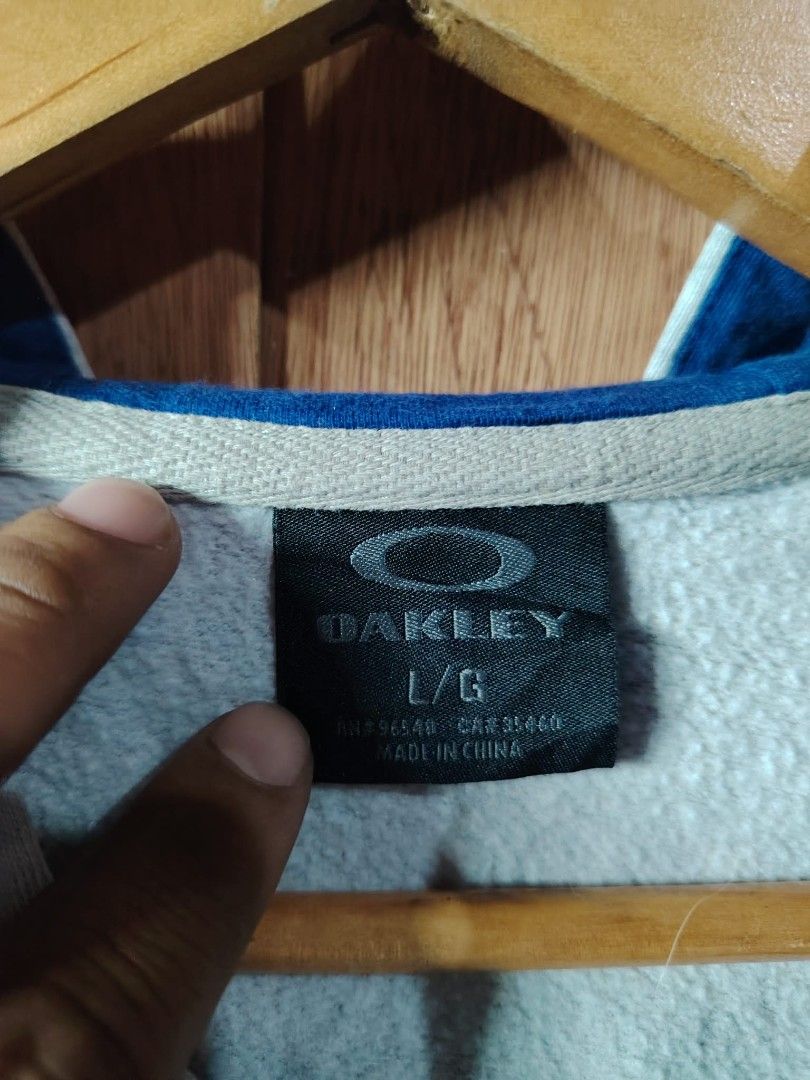 Oakley Full Zip Hoodie Grey Size Large (Category: Coats, Jackets and Outerwear) located in Manila. Submitted by tabuzomaria1422 (Listing ID 1469447590, Image 3). Description: - Brand: Oakley - Style: Full Zip Hoodie - Color: Grey with dark blue & orange chest logo - Size: Large - Material: Comfortable cotton and polyester blend - Features: Adjustable hood drawstrings and front kangaroo pockets - Care: Machine washable - Origin: Made in China.