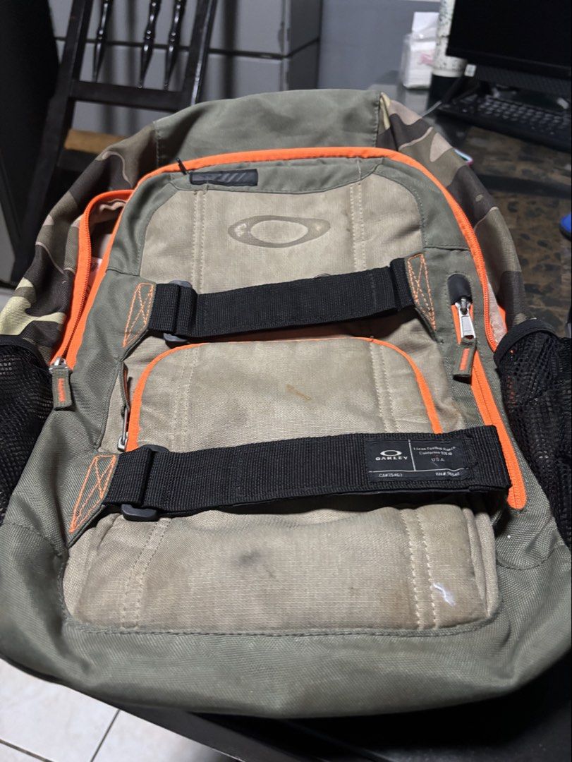 Oakley Olive Green Backpack with Orange Accents (Category: Backpacks) located in Manila. Submitted by markjoy712 (Listing ID 1469400458, Image 1). Description: - Authentic Oakley backpack in olive green with striking bright orange trim - Features iconic Foothill Ranch, California logo patch and black utility straps - Equipped with multiple zippered compartments and convenient mesh side pockets - Dual horizontal strapping system for extra gear and