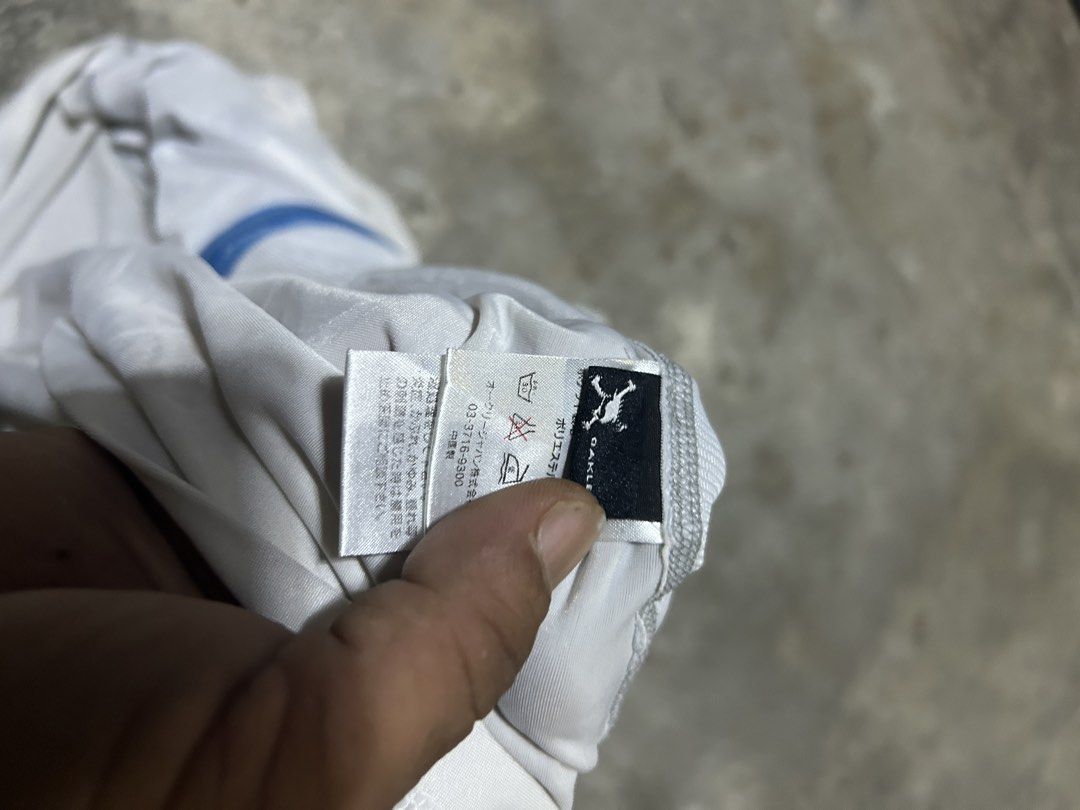 Oakley White Hooded Jacket Full Zip Size L (Category: Coats, Jackets and Outerwear) located in Manila. Submitted by andotputla37237 (Listing ID 1469515772, Image 3). Description: - Brand: Oakley - Style: Full-zip athletic hoodie - Size: Large (checked via neck tag) - Color: Crisp white with vibrant blue accents - Details: Blue zipper, blue logo graphic on left chest, attached hood, and two functional front pockets - Material: Lightweight, breatha