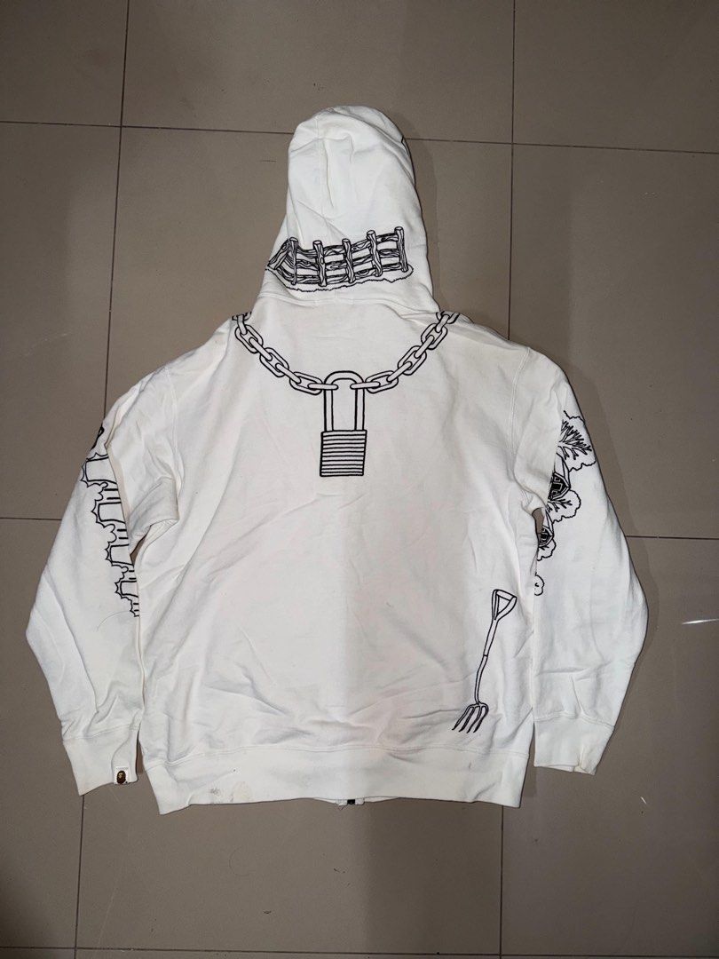 OG BAPE HOLSTEIN COW FULL ZIP (Category: Hoodies) located in Manila. Submitted by sleamdaily222 (Listing ID 1469555021, Image 2). Description: - Color: White with unique graphic prints - Design: Full-face cartoon graphic on hood, chain prints around neck, farmhouse prints on sleeves, cow spot outlines on front pockets, and back padlock detail - Hardware: Double zipper - Condition: Pre-owned with minor yellowing stains on the front and near the po