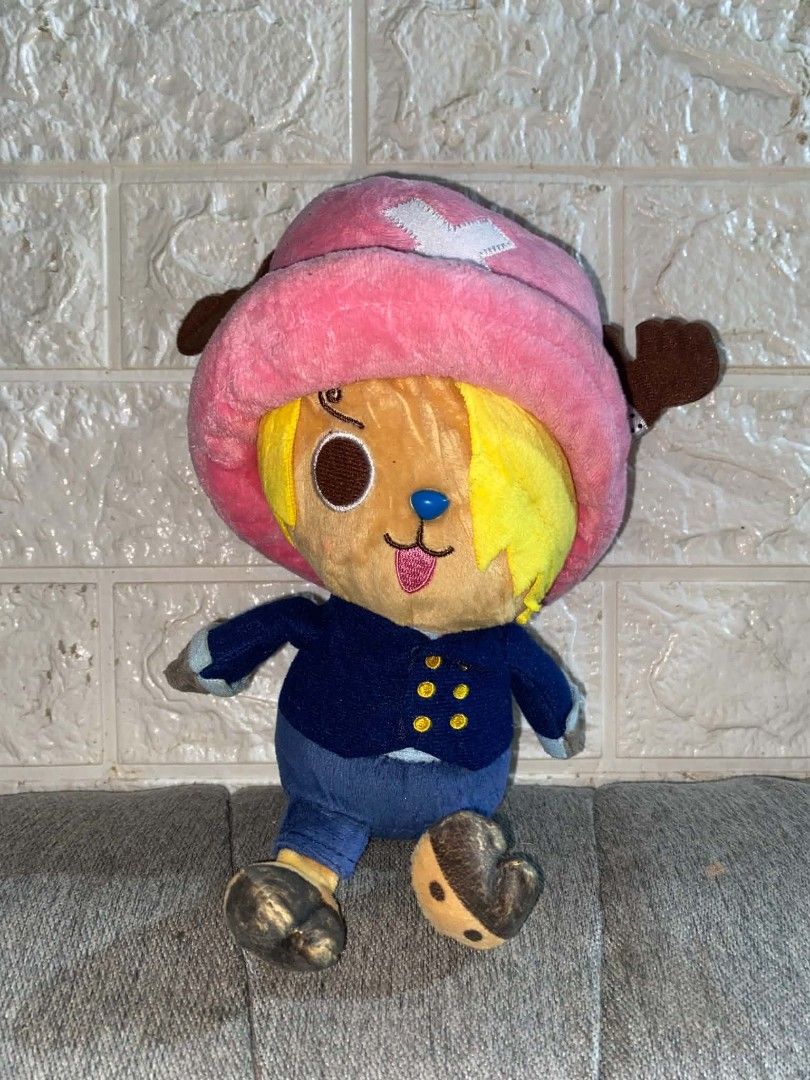 One Piece Chopper Sanji Crossover Plush Toy (Category: Plushies & Soft Toys) located in Talavera. Submitted by jb_alvarez1 (Listing ID 1469517944, Image 1). Description: - Character: Tony Tony Chopper mashed up with Sanji - Features: Blonde hair, spiral eyebrow, blue suit jacket, and pink reindeer hat - Authenticity: Official licensed merchandise with Eiichiro Oda, Shueisha, and Toei Animation tags - Material: Soft fabric, sitting pose - Conditio