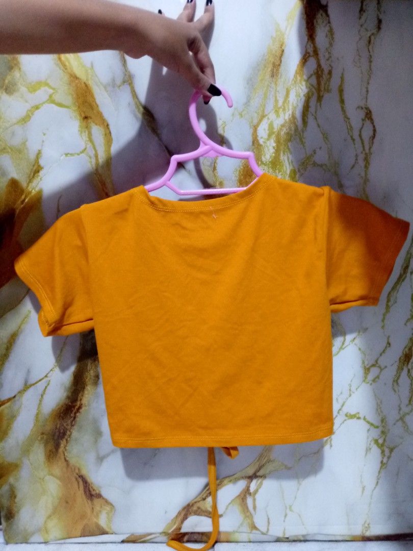 Orange Ruched Crop Top with Drawstring XS-S (Category: Sleeveless) located in Taguig. Submitted by anika_francine (Listing ID 1469493724, Image 2). Description: - Color: Vibrant orange - Style: Crop top with short sleeves and waist-length fit - Neckline: Deep V-neck with ruched drawstring center and dangling ties - Back: Plain design - Fabric: Stretchy, comfortable, and easy to pair with high-waisted jeans or skirts - Condition: Clean and ready t