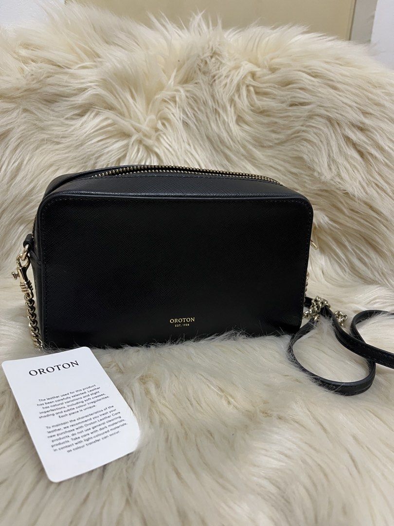 Oroton Black Crossbody Camera Bag with Chain Strap (Category: Cross-body Bags) located in Naga. Submitted by ownlineshopp (Listing ID 1469504209, Image 1). Description: - Brand: Oroton - Style: Sling bag - Material: Premium pebbled leather - Color: Classic black with elegant gold-tone hardware - Closure: Secure zip top - Strap: Removable strap featuring a stylish mix of chain links and leather - Branding: Subtle gold embossed logo on the front - 