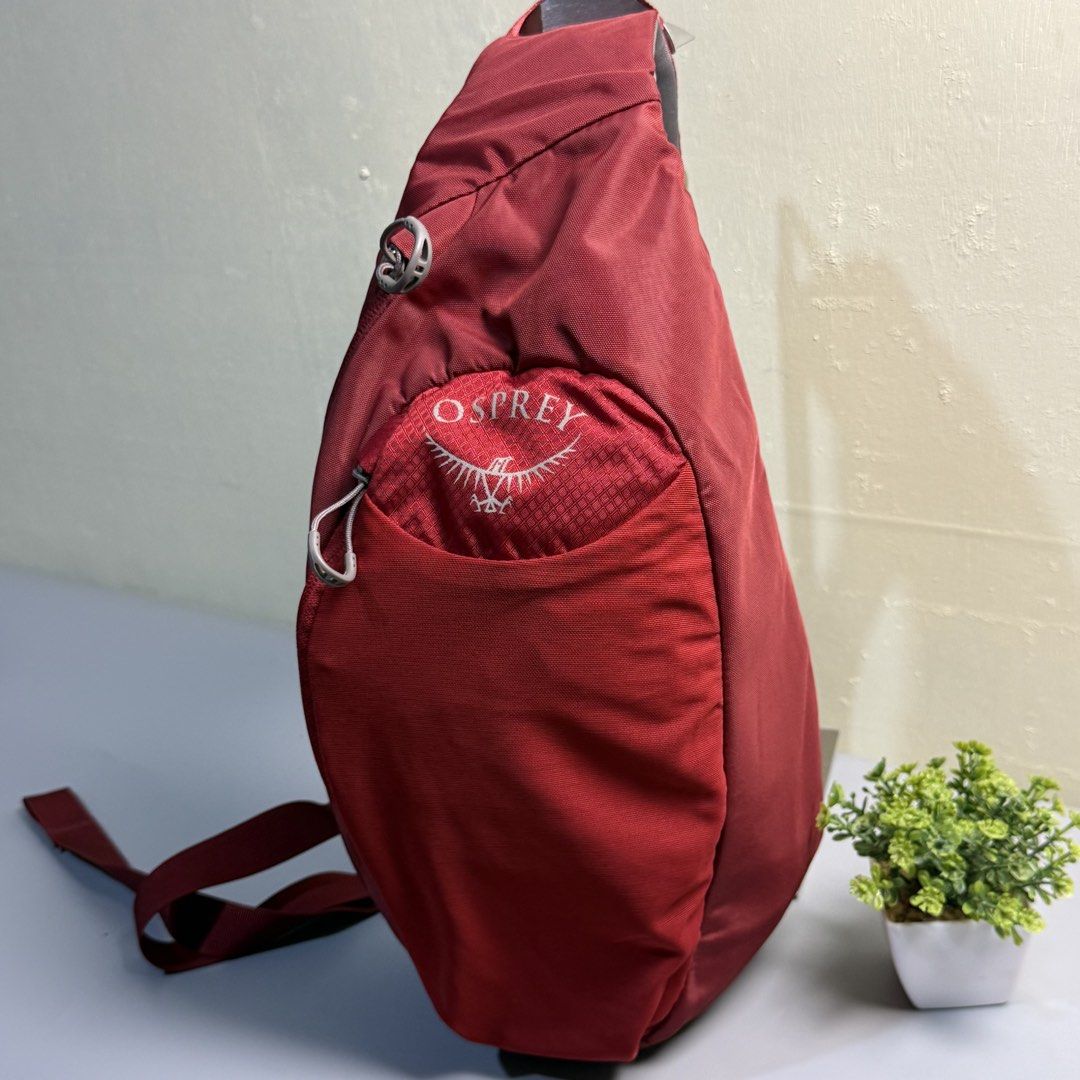 Osprey Daylite Sling Backpack Red Maroon (Category: Backpacks) located in Bago City. Submitted by g___shop (Listing ID 1469500560, Image 2). Description: - Brand: Osprey (Daylite Sling Bag) - Color: Red with grey patterned mesh details - Design: Compact teardrop shape with a sturdy, adjustable single strap and small buckle clip - Compartments: Front zippered pocket and spacious main compartment for everyday essentials - Comfort: Breathable grey b
