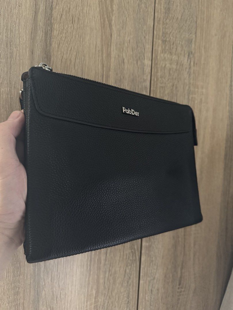 Men’s PabDer Black Leather Clutch Bag (Category: Belt bags, Clutches and Pouches) located in Mandaluyong City. Submitted by raykin (Listing ID 1469446312, Image 1). Description: Authentic black pebbled leather clutch from PabDer in clean condition. Features silver hardware, a secure top zip, a front flap pocket with a metal logo, and a brown-lined interior with an extra zip pocket. Please check the photos for the size reference against Meralco bi