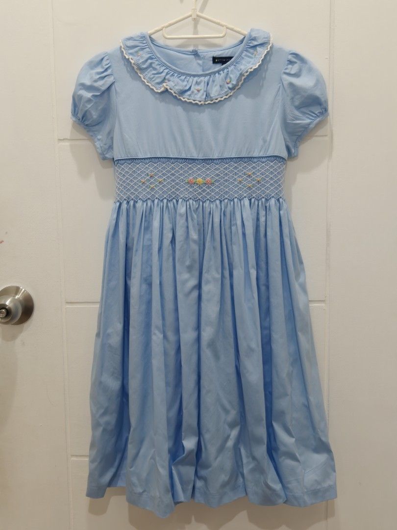 Periwinkle Blue Smocked Dress Size 12Y (Category: Babies & Kids Fashion) located in Cebu City. Submitted by periwinkletwinkles (Listing ID 1469448570, Image 1). Description: - Brand: Periwinkle - Size: 12Y (fits older kids) - Color: Light Blue - Material: 100% Cotton - Design: Smocked chest with tiny floral embroidery, white ruffled collar, and puffed short sleeves - Closure: Back buttons with a matching attached waist sash - Condition: Excellent