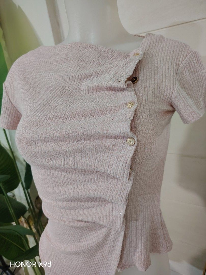 Pink Asymmetrical Hem Top with Buttons (Category: Shirts) located in Mabalacat. Submitted by Jackikay.PreLoved (Listing ID 1469516006, Image 3). Description: Note: 2 missing buttons :( Change the buttons na lang. P'wede sa madiskarte! - Color: Cute pastel pink - Style: Fitted short-sleeve top with a trendy asymmetrical hemline - Details: Decorative gold-toned buttons along the front pleat - Fabric: Soft, stretchy, and comfortable knit material - 