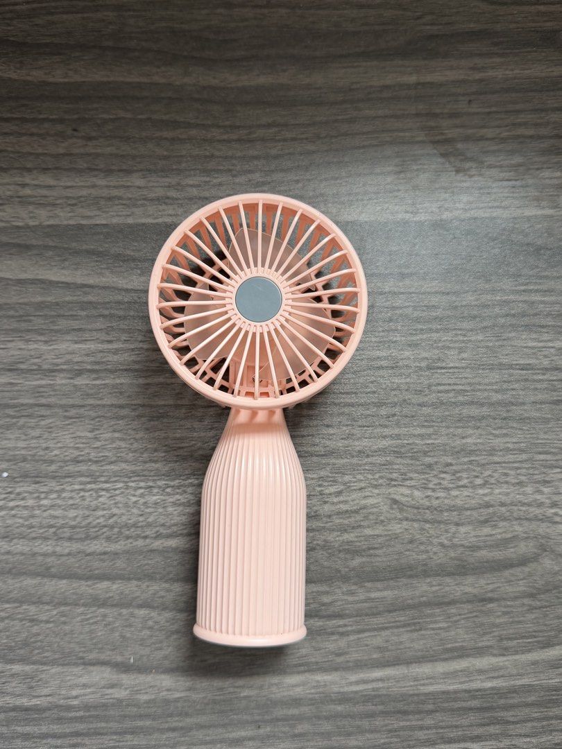 Pink portable handheld fan with built-in LED light (Category: Fans) located in Quezon City. Submitted by giaaaaa123 (Listing ID 1469426766, Image 1). Description: - Negotiable - Color: Stylish pink with a comfortable ribbed handle grip - Rechargeable battery operation for convenient daily use - Versatile folding head design for easy packing - Built-in LED light on the back spine for extra illumination - Compact size fits easily into any bag for t