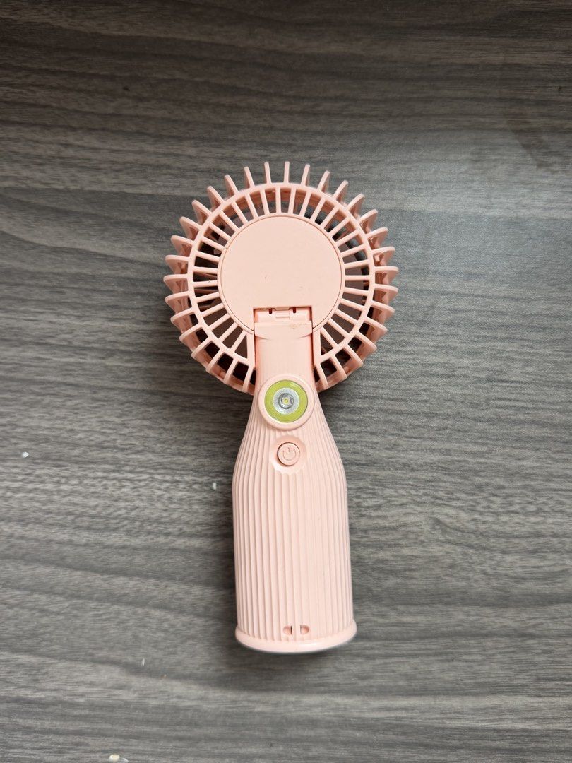 Pink portable handheld fan with built-in LED light (Category: Fans) located in Quezon City. Submitted by giaaaaa123 (Listing ID 1469426766, Image 2). Description: - Negotiable - Color: Stylish pink with a comfortable ribbed handle grip - Rechargeable battery operation for convenient daily use - Versatile folding head design for easy packing - Built-in LED light on the back spine for extra illumination - Compact size fits easily into any bag for t