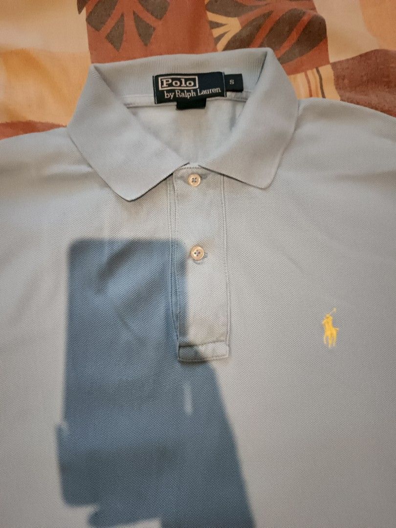 Polo Ralph Lauren (Category: Activewear) located in Odiongan. Submitted by thriftngo26 (Listing ID 1469403263, Image 2). Description: This is a classic Polo Ralph Lauren light blue piqué polo shirt featuring the signature yellow embroidered Polo Pony motif on the chest. This short-sleeve style includes a two-button placket, ribbed collar, and small side slits at the hem.