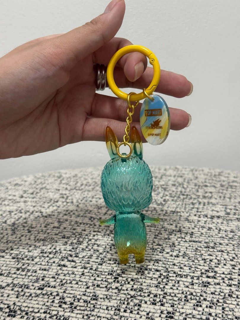 Pop Mart The Monsters Vinyl Face Keychain (Category: Designer & Blind Box Toys) located in Taguig. Submitted by kittychum (Listing ID 1469531315, Image 2). Description: New but opened and no more box 💯Authentic Pop Martin This is the Labubu & Spooky figure keychain from the Pop Mart The Monsters 10th Anniversary Series. The translucent, teal-to-yellow gradient vinyl character features pointed orange-yellow ears, purple eyes, and a cheerful-to-mi