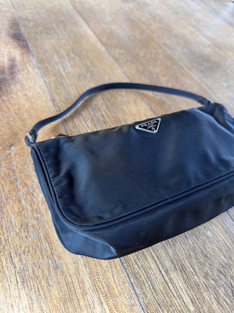 PRADA Nylon Pochette (Category: Luxury Bags & Wallets) located in Davao. Submitted by _iconculture (Listing ID 1469523698, Image 2). Description: AVAILABLE • PRADA Tessuto Nylon Pochette ★ A true classic that never goes out of style. Condition: 9.8/10 — Almost mint condition! Has minor dirt marks on the body that may be removed with proper cleaning. Clean interior. Small but mighty, she can fit your iPhone Pro Max, wallet, and other daily essenti