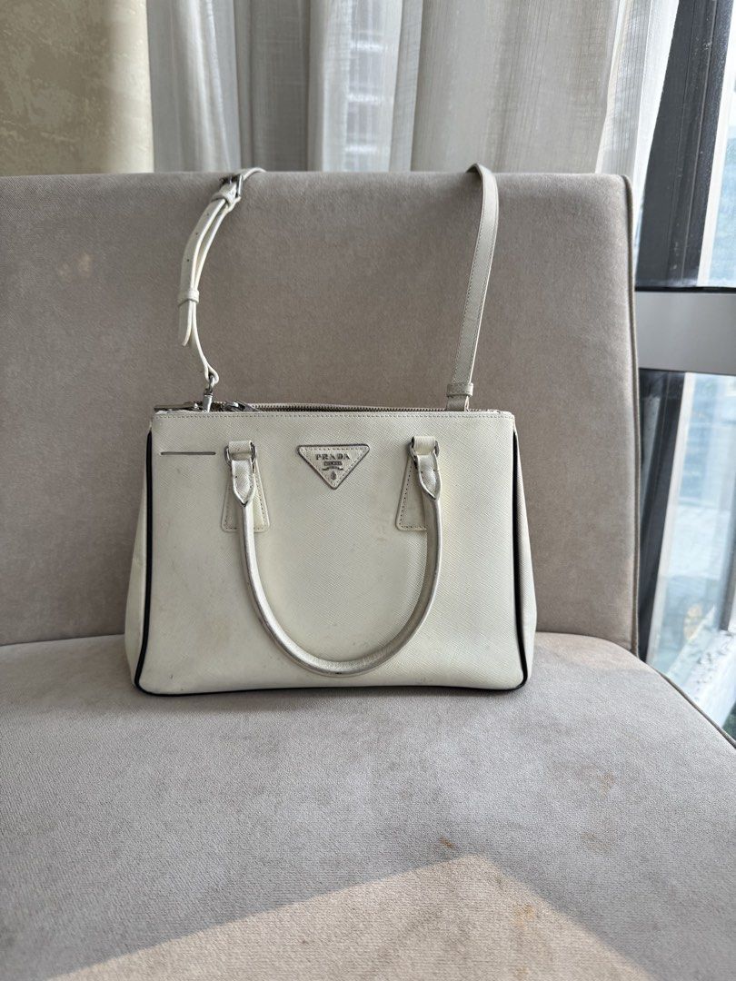 Prada Saffiano Leather Tote Bag White (Category: Luxury Bags & Wallets) located in Paranaque City. Submitted by piemumbuys (Listing ID 1469465271, Image 1). Description: - Authentic Prada Saffiano leather handbag in classic white - Silver-tone hardware featuring the iconic front triangle logo - Dual top handles and a convenient detachable shoulder strap - Secure zip-top closure leading to a black-lined interior with the Prada Milano metal plaque 